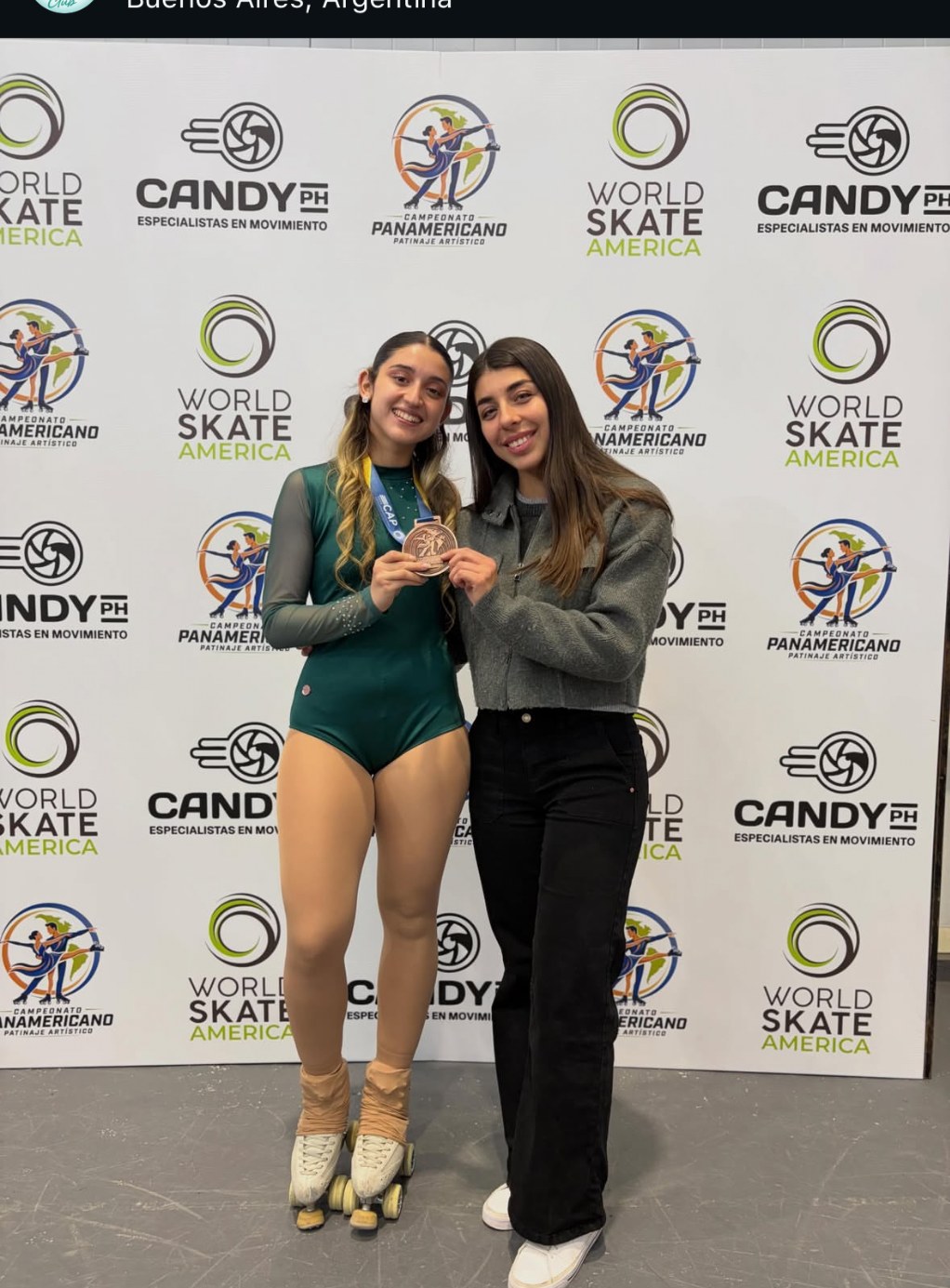 Patinadora del club mostrando una medalla junto a una acompañante